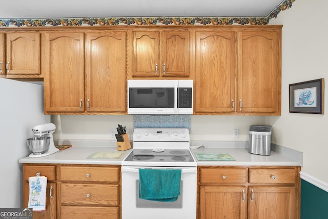 kitchen featuring white appliances, light countertops, and brown cabinetry