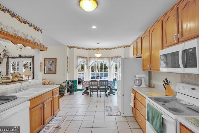 kitchen with hanging light fixtures, white appliances, light countertops, and a sink