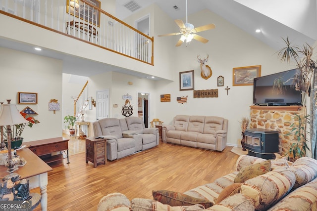 living room with light wood-type flooring, a wood stove, visible vents, and stairs