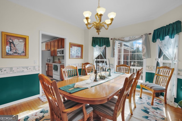 dining area featuring light wood-style floors, a chandelier, ornamental molding, and baseboards