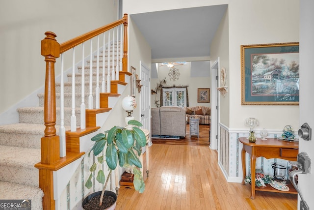 foyer entrance featuring a wainscoted wall, a ceiling fan, stairway, and wood finished floors