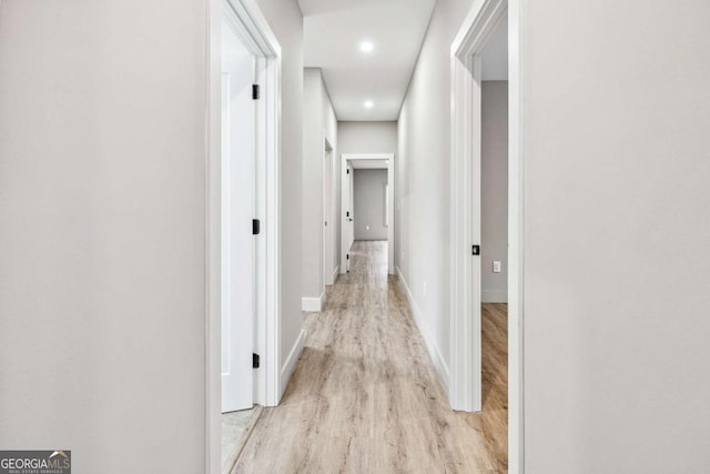 corridor with light wood finished floors and baseboards