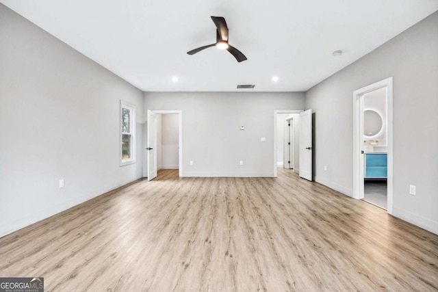 interior space with a ceiling fan, light wood-type flooring, visible vents, and baseboards