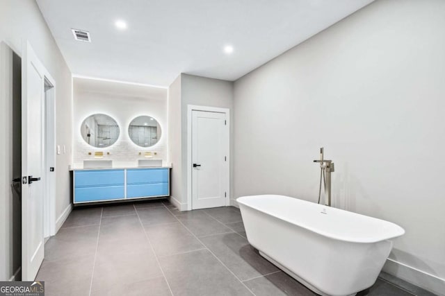 full bathroom with double vanity, visible vents, tile patterned flooring, a freestanding tub, and baseboards