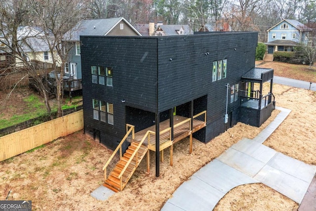 exterior space featuring a shingled roof, fence, a deck, and stairs