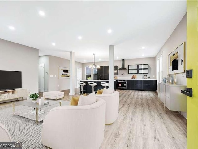 living room featuring plenty of natural light, light wood finished floors, recessed lighting, and a notable chandelier