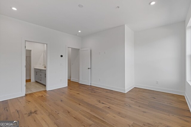 unfurnished bedroom featuring light wood finished floors, baseboards, recessed lighting, and ensuite bathroom