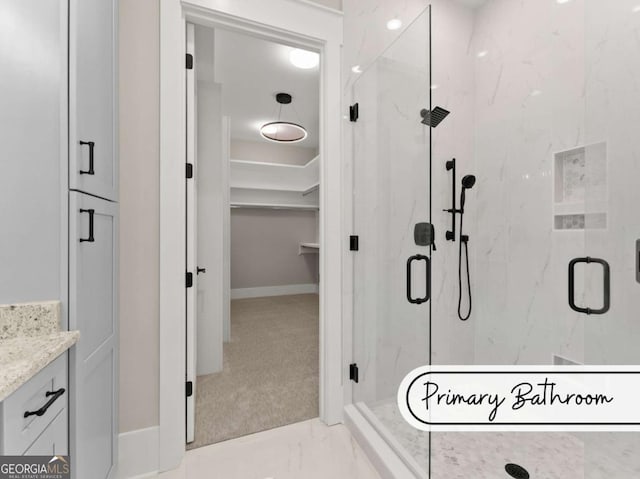 full bathroom with marble finish floor, a spacious closet, a marble finish shower, and vanity