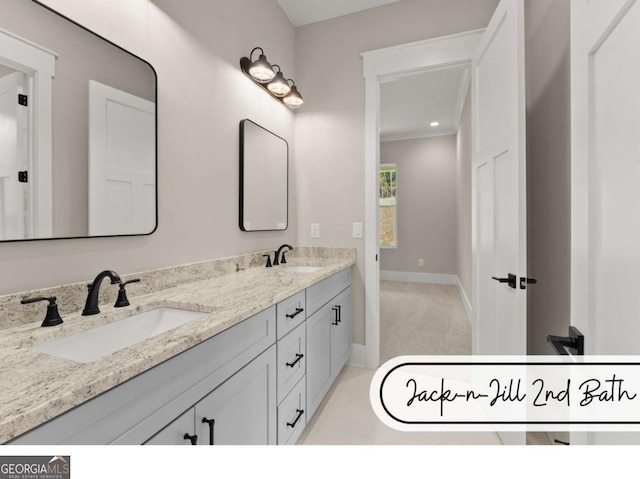 full bathroom with double vanity, baseboards, and a sink