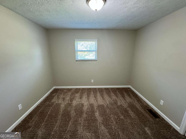 spare room featuring a textured ceiling, carpet, visible vents, and baseboards