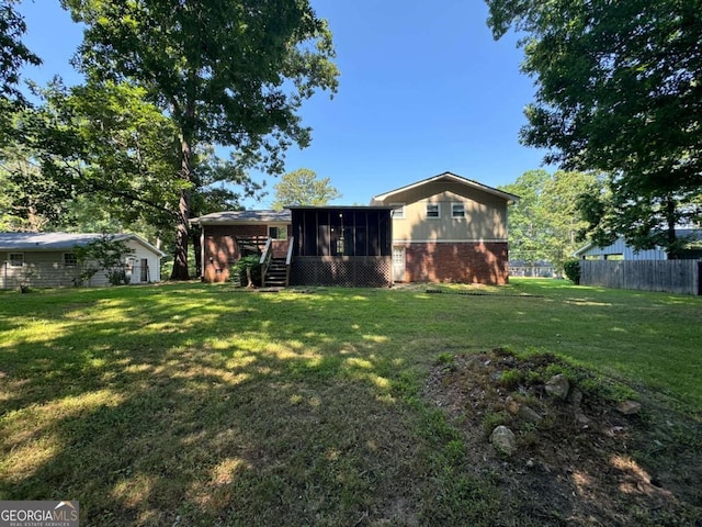 rear view of property featuring a yard, brick siding, fence, and a sunroom