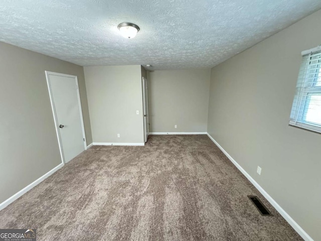 carpeted empty room featuring baseboards, visible vents, and a textured ceiling