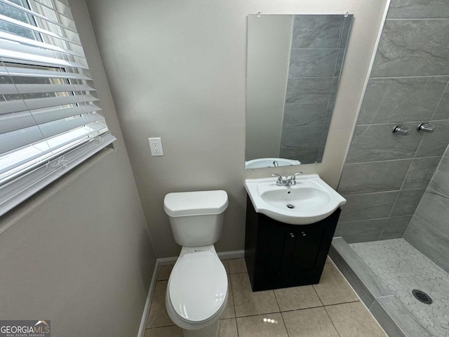 bathroom featuring toilet, a shower stall, vanity, tile patterned flooring, and baseboards