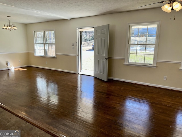 interior space featuring dark wood-style floors, a textured ceiling, baseboards, and ceiling fan with notable chandelier