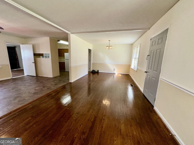 unfurnished living room with baseboards, dark wood-style flooring, visible vents, and an inviting chandelier