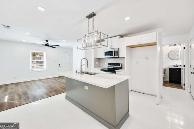 kitchen featuring visible vents, a sink, tasteful backsplash, stainless steel appliances, and white cabinets