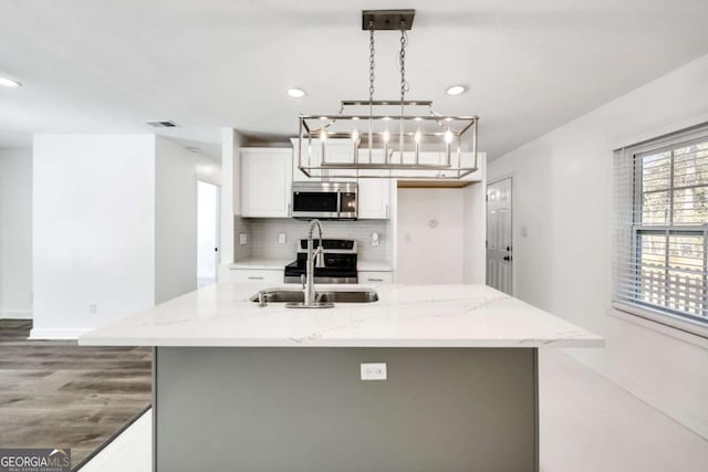 kitchen featuring decorative backsplash, appliances with stainless steel finishes, white cabinetry, and light stone countertops