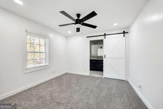 unfurnished bedroom with recessed lighting, baseboards, carpet, and a barn door