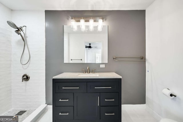 full bathroom with a tile shower, vanity, and a ceiling fan