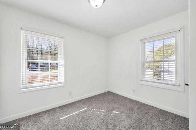 carpeted spare room with a healthy amount of sunlight and baseboards