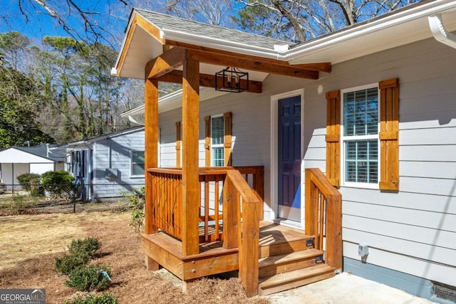 property entrance with a porch, fence, and a shingled roof