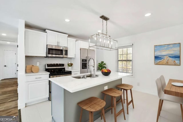 kitchen with a sink, tasteful backsplash, stainless steel appliances, a breakfast bar area, and light countertops