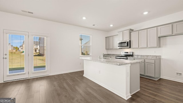 kitchen with appliances with stainless steel finishes, an island with sink, visible vents, and gray cabinetry