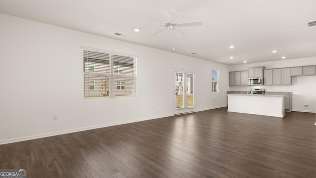 unfurnished living room featuring recessed lighting, dark wood-style flooring, a ceiling fan, visible vents, and baseboards