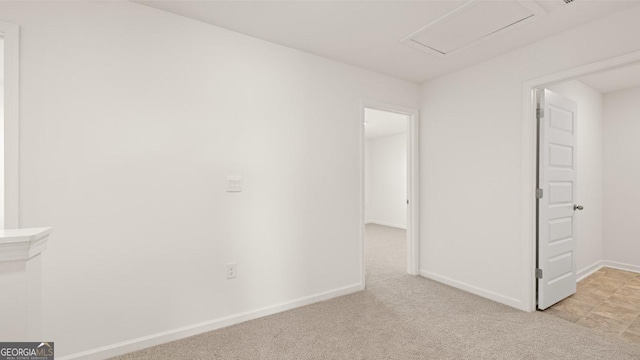 empty room with light carpet, attic access, and baseboards