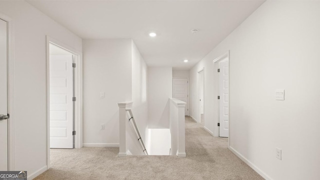 hallway with light carpet, baseboards, an upstairs landing, and recessed lighting