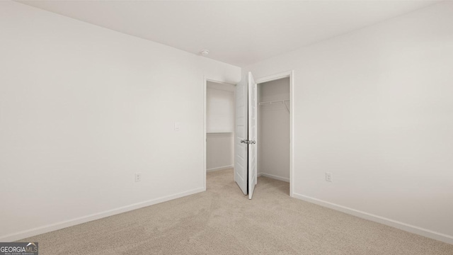 unfurnished bedroom with baseboards, a closet, and light colored carpet