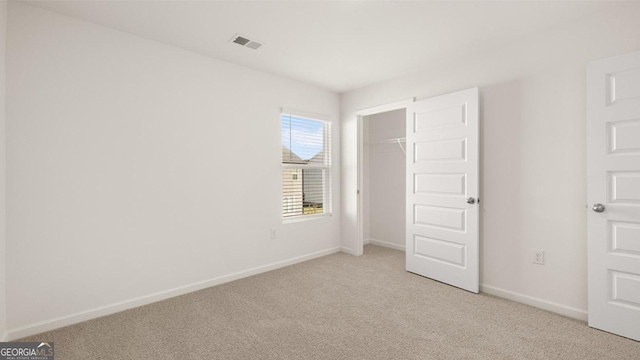 unfurnished bedroom featuring baseboards, visible vents, a closet, and light colored carpet