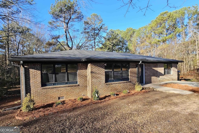 view of side of property with brick siding, crawl space, and driveway