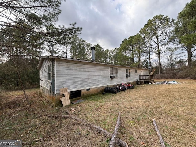 view of side of property with crawl space and a lawn