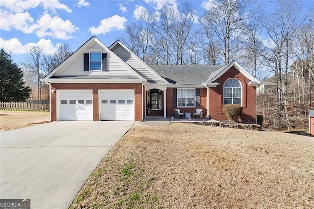 view of front of property featuring a garage, driveway, brick siding, and fence