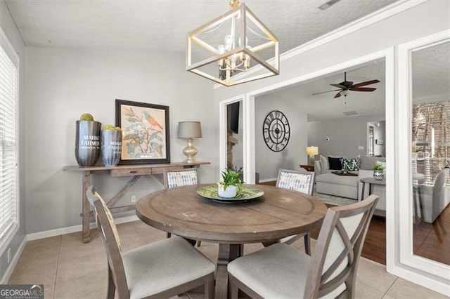 dining area featuring baseboards, lofted ceiling, light tile patterned flooring, a textured ceiling, and ceiling fan with notable chandelier