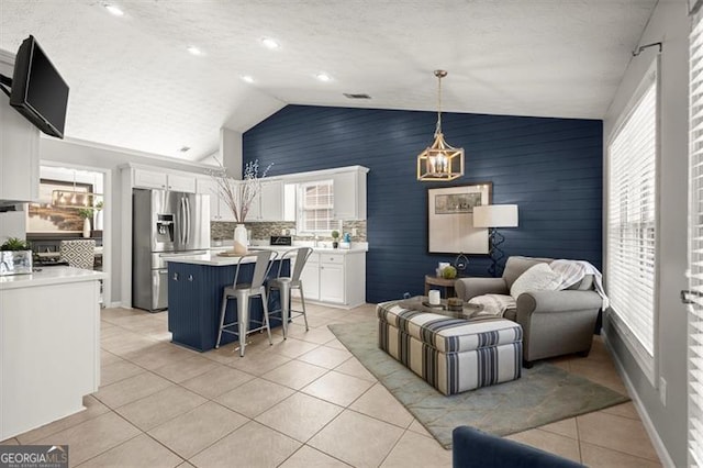 living room featuring lofted ceiling, light tile patterned floors, baseboards, and visible vents