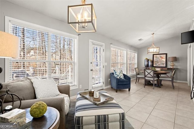 living room with a chandelier, lofted ceiling, light tile patterned flooring, and baseboards