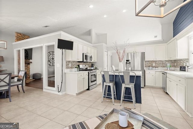 kitchen with white cabinets, a kitchen island, stainless steel appliances, and light countertops