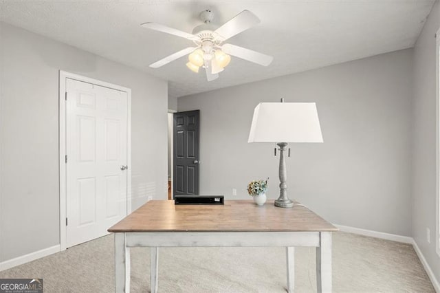 unfurnished office featuring light carpet, ceiling fan, and baseboards