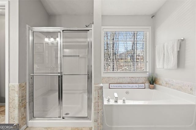 bathroom featuring a shower with door, a garden tub, and a textured ceiling