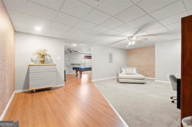 sitting room featuring a drop ceiling, wood finished floors, and baseboards