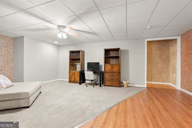 carpeted office with a drop ceiling, wood finished floors, and baseboards