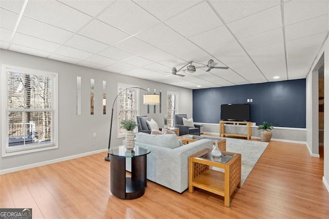 living room featuring a paneled ceiling, a ceiling fan, baseboards, and wood finished floors