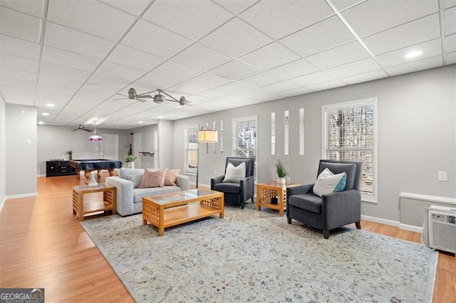 living room with a drop ceiling, wood finished floors, and baseboards