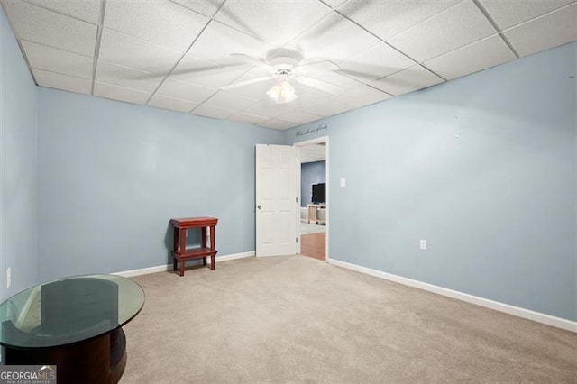 living area with carpet, a paneled ceiling, and baseboards