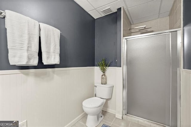 bathroom featuring visible vents, toilet, a wainscoted wall, tile patterned floors, and a shower stall