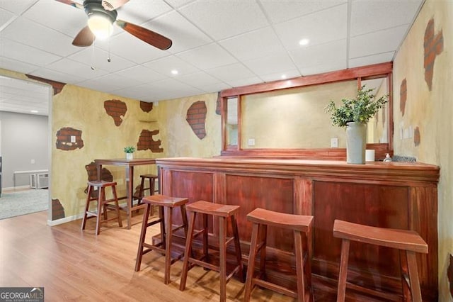 bar featuring light wood-type flooring, a drop ceiling, a dry bar, and recessed lighting