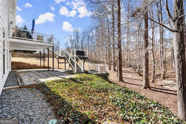 view of yard featuring stairs, a patio area, a wooden deck, and fence