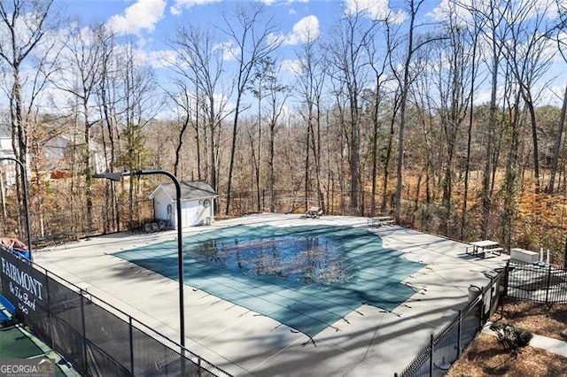 view of swimming pool with an outdoor structure, a patio area, fence, and a fenced in pool